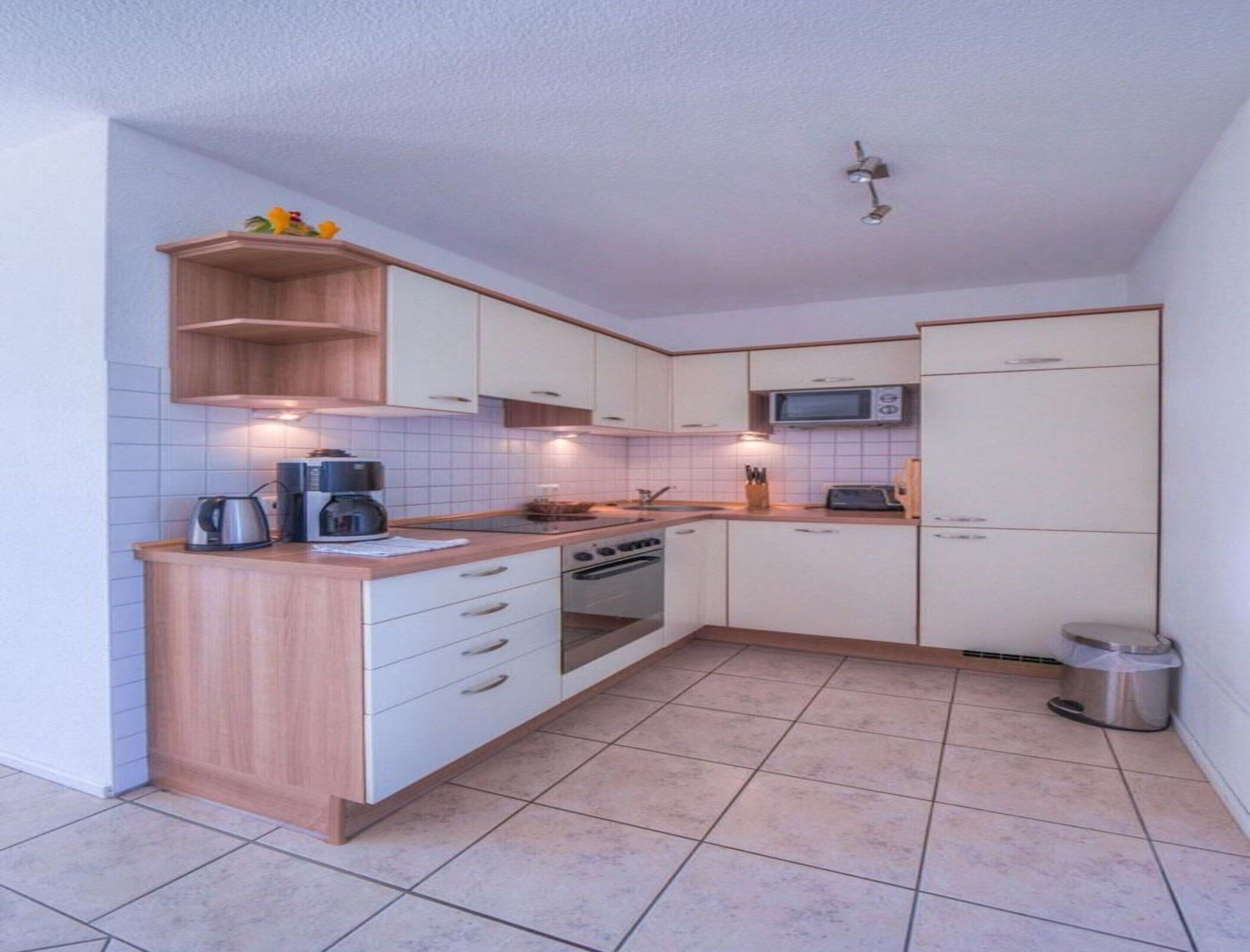 A compact kitchen with white cabinets, a microwave, a stove, and a coffee maker.