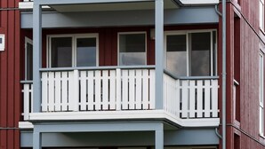 En flereetagers boligbygning med altaner, store vinduer og rød facade.