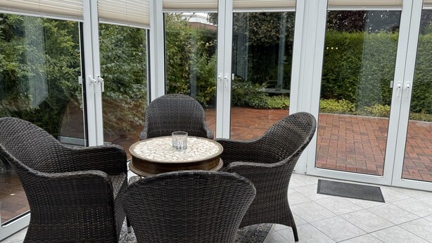 A conservatory with a glass door, wicker furniture, and a tiled floor. - Bungalow, Dornumersiel (Dornum)
