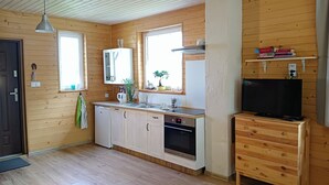 Une cuisine compacte aux murs en bois, dotée d’un four encastré, d’un évier et d’un petit téléviseur posé sur un meuble en bois.