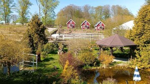 Un paysage rural avec trois granges rouges, un étang et un kiosque.