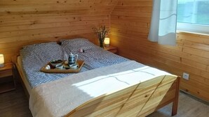 Une pièce chaleureuse en bois, avec un lit, une table de chevet et une fenêtre avec des rideaux.