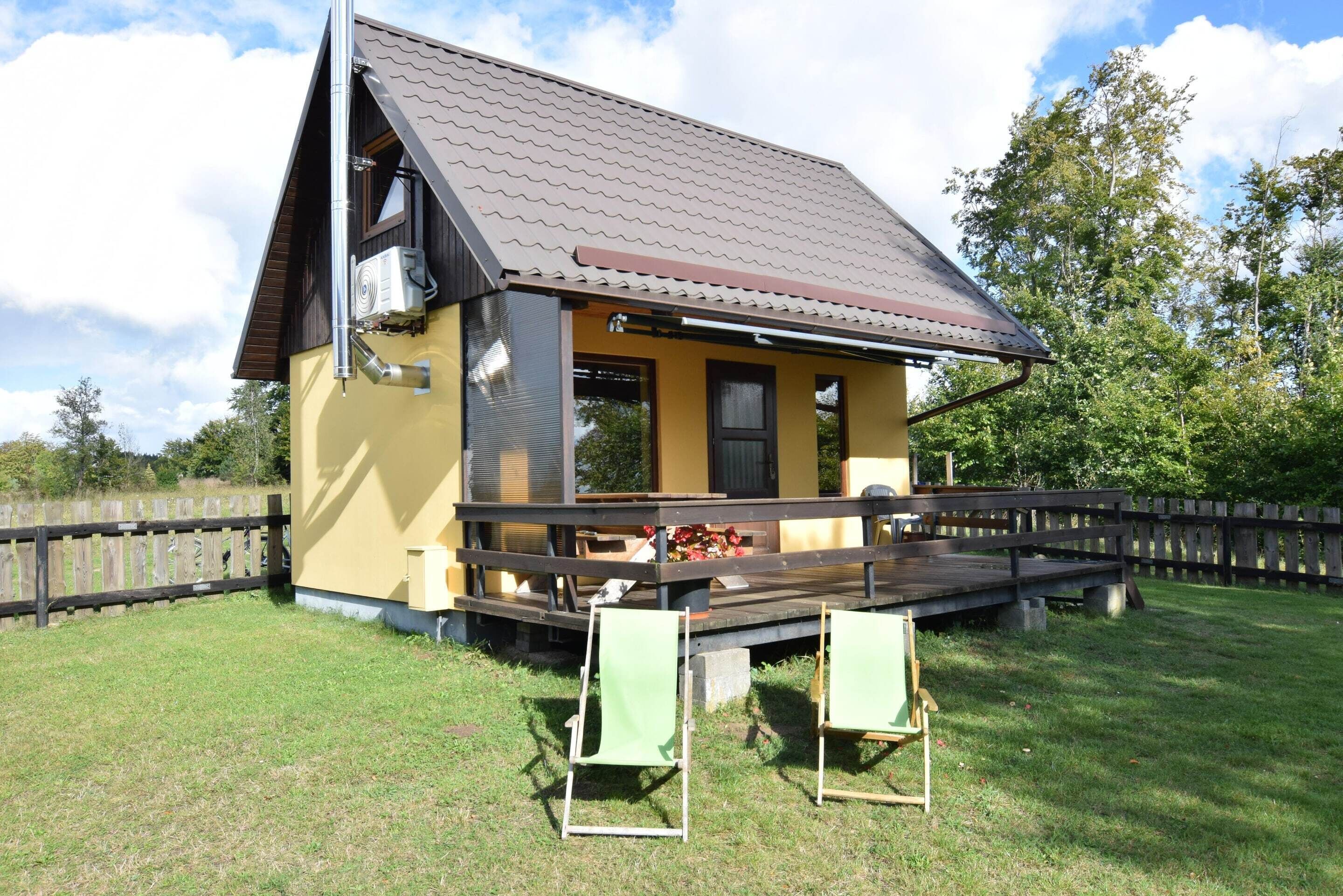 Un bâtiment jaune avec un toit marron et une terrasse en bois.