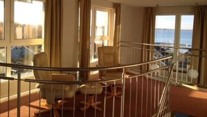 A hotel room with a balcony, large windows, and a view of the sea. - Geschmackvoll Eingerichtetes Appartement (Rechlin)