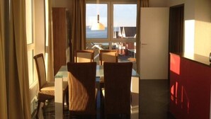 A hotel room with a dining area, large windows, and a view of the sea. - Geschmackvoll Eingerichtetes Appartement (Rechlin)