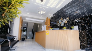 Un taulell de recepció modern amb acabat de fusta, un cartell de prohibició de fumar i una paret de marbre negre amb elements decoratius.