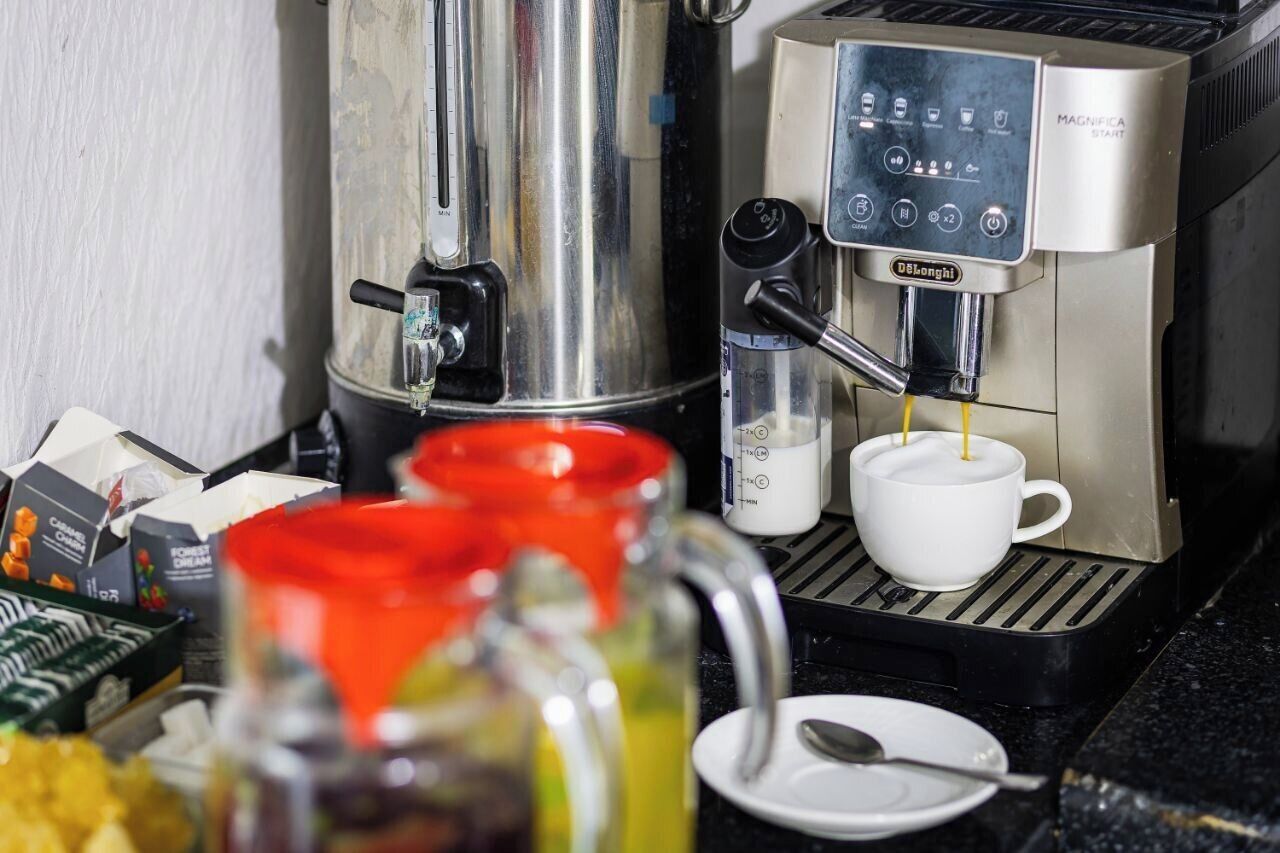 A coffee machine with a digital interface, a milk frother, and a coffee pot.