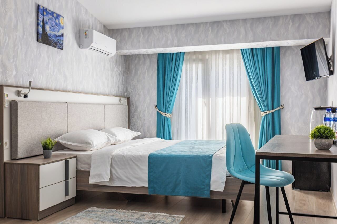 A modern bedroom with a bed, bedside table, chair, and a desk with a chair.