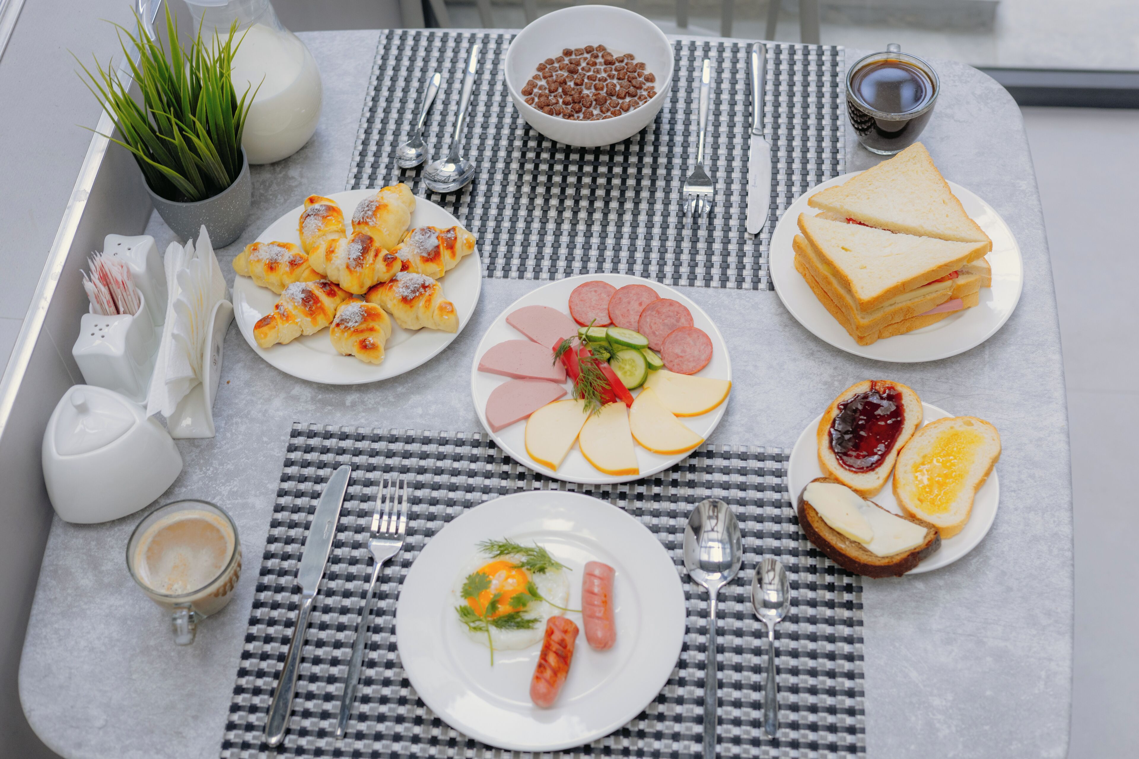 A breakfast table with plates of food, cutlery, and a coffee cup.