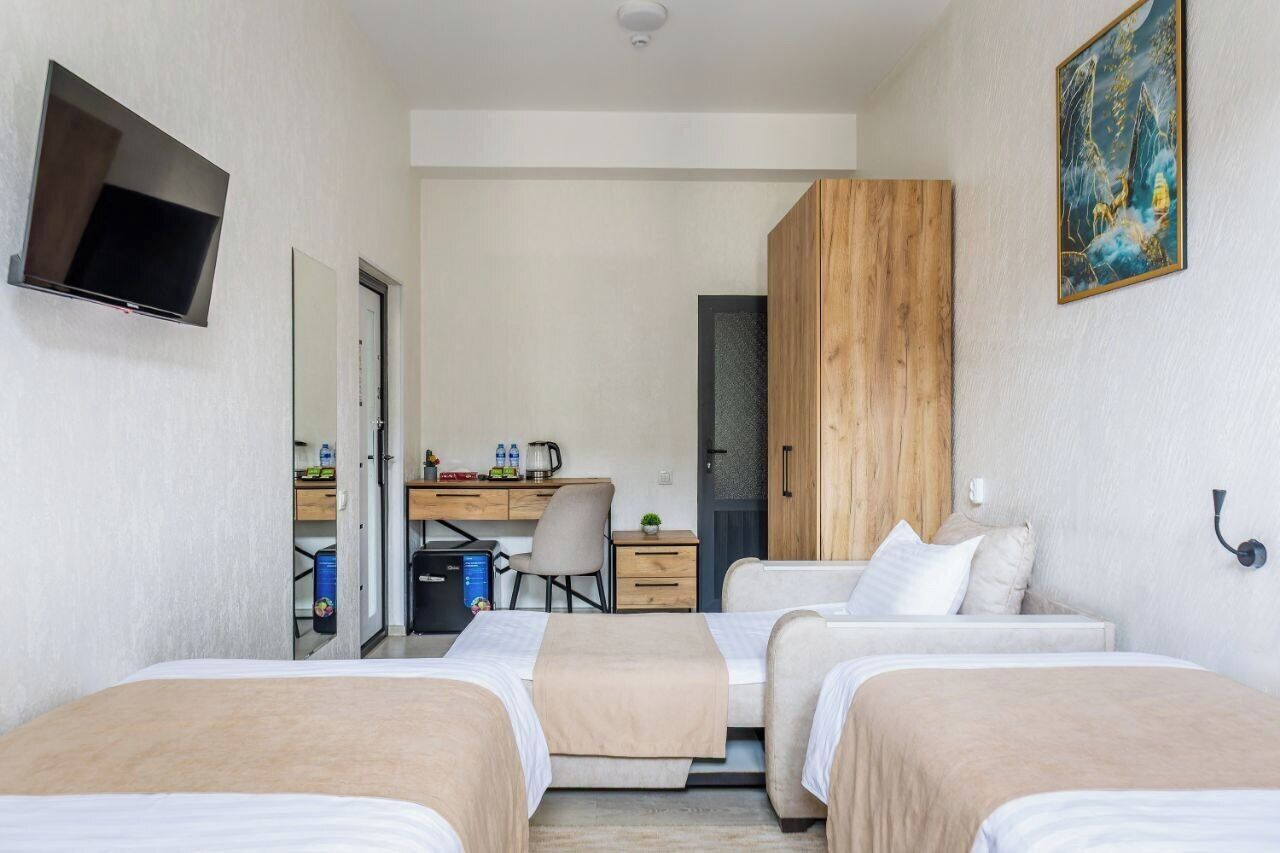 A hotel room with two beds, a desk, a TV, and a wardrobe.
