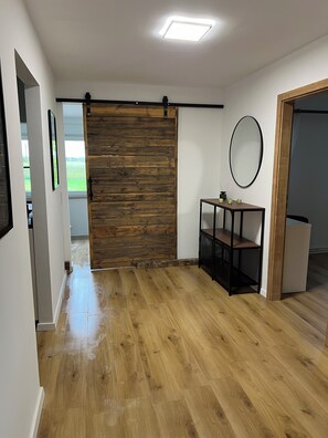 A modern interior with a wooden wall, a small table with a mirror, and a door leading to another room. - Vacation home unterm Kohnstein (Nordhausen)