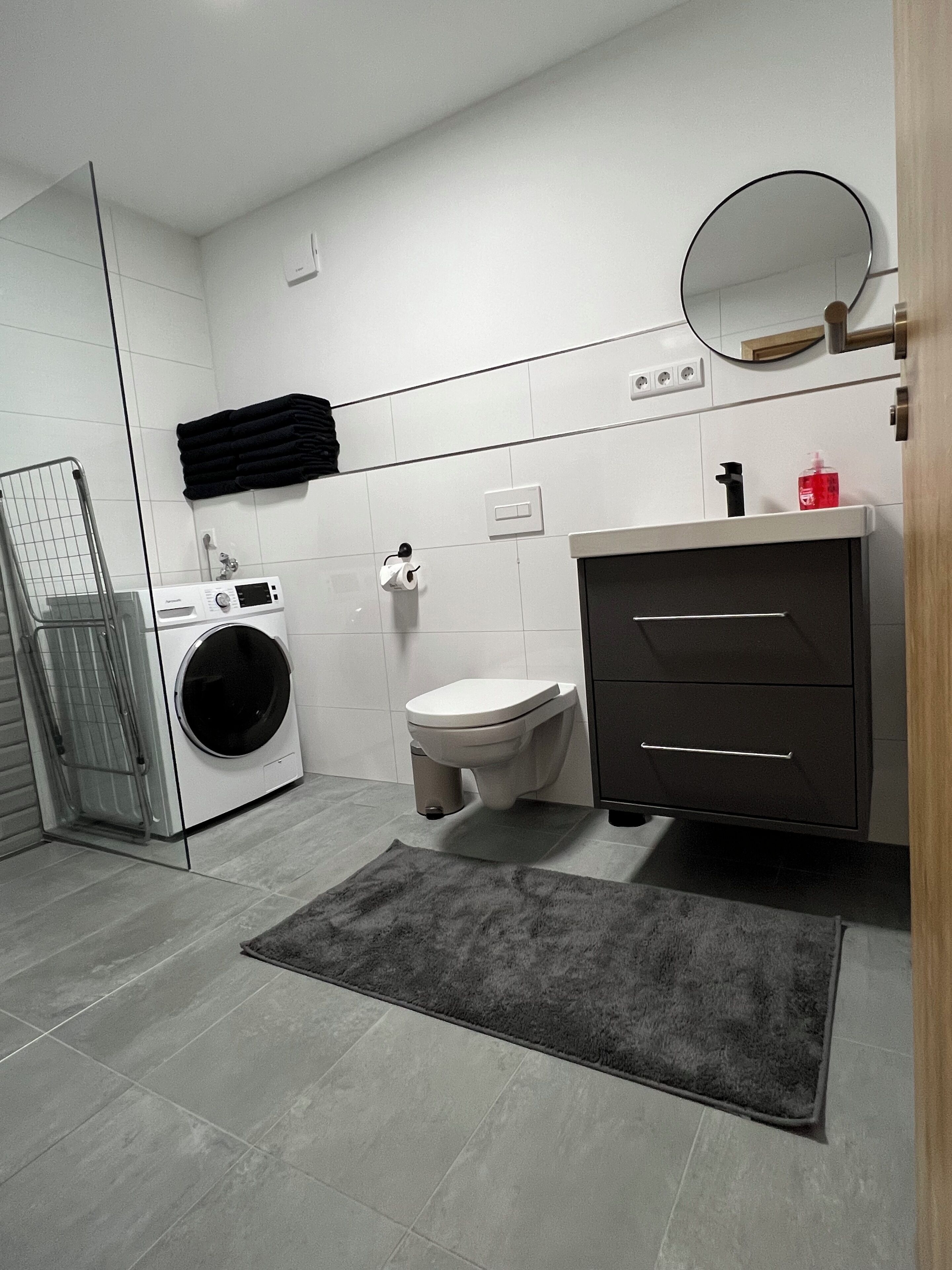 Un bagno moderno con lavatrice, toilette e lavandino con specchio.