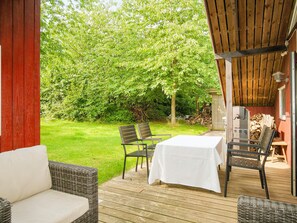 An outdoor patio with wicker furniture, a table, and a grill. - 4 Person Holiday Home in Gilleleje (Gilleleje)
