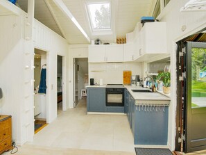 A compact kitchen with white cabinets, a blue island, and a built-in oven. - 4 Person Holiday Home in Gilleleje (Gilleleje)