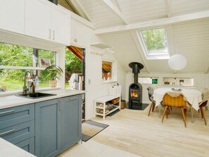 A modern kitchen with a built-in stove, a dining area with a round table, and a view of the outdoors. - 4 Person Holiday Home in Gilleleje (Gilleleje)