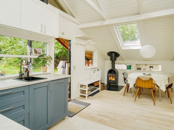 A kitchen with a built-in stove, a dining area with a round table, and a view of the outdoors. - 4 Person Holiday Home in Gilleleje (Gilleleje)