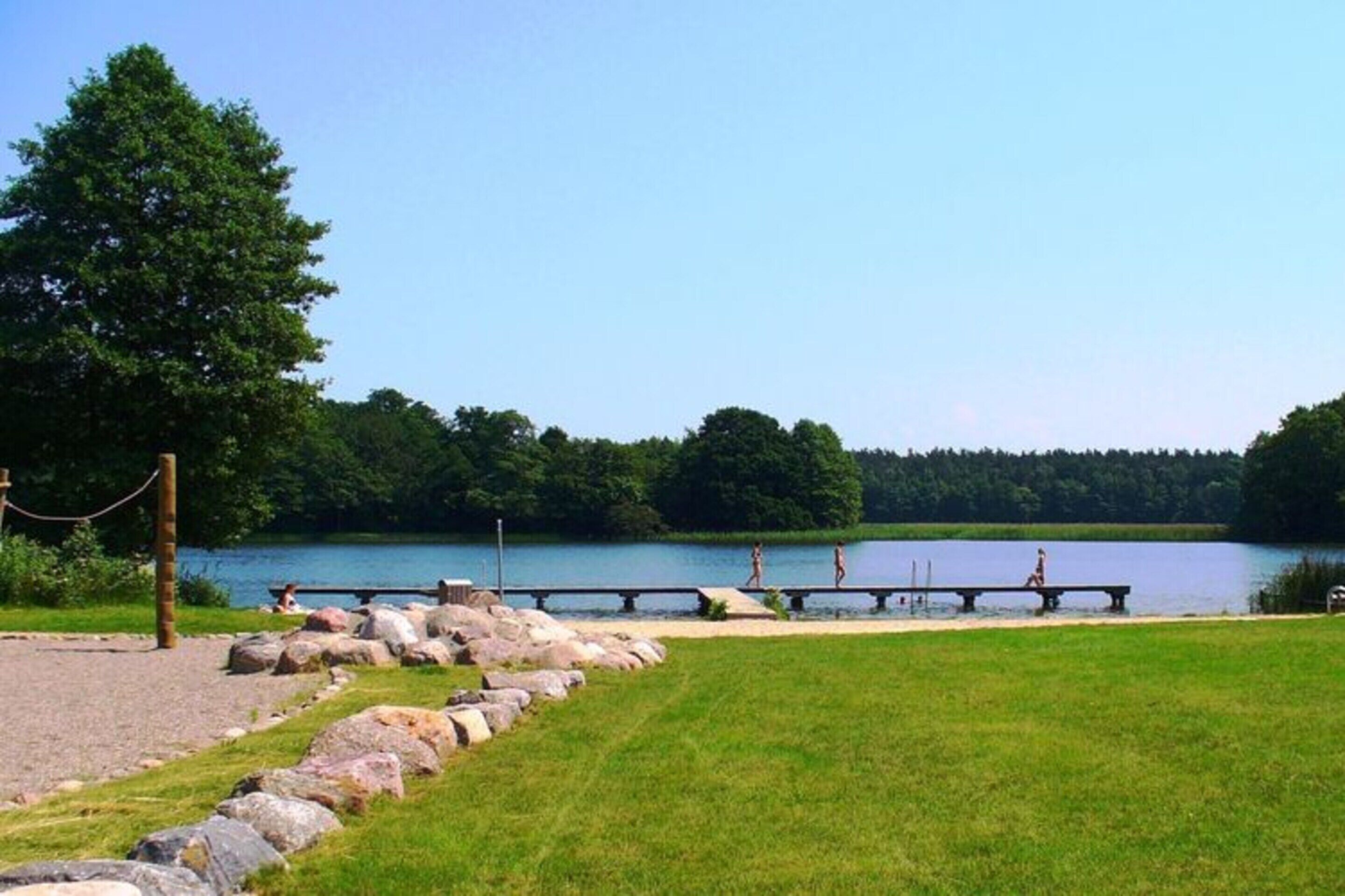 Un parc au bord du lac, doté d’une terrasse en bois, de tables de pique-nique et d’une pelouse.