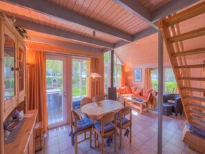 A cozy room with a wooden ceiling, a dining area with a round table and chairs, and a sofa set. - Skandinavisches Ferienhaus in Rechlin (Rechlin)