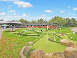 Egy miniatűr golfpálya, a háttérben egy épülettel.