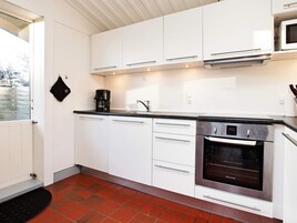 A modern kitchen with white cabinets, a stainless steel oven, and a black coffee maker.