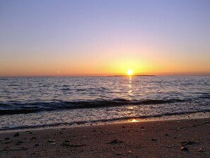 Une plage au coucher du soleil, avec une eau calme et un ciel dégagé.