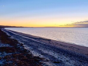 Une plage avec un ciel dégagé et une eau calme.