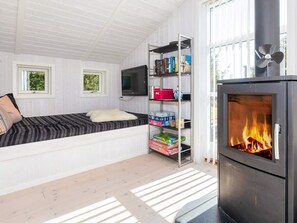 A cozy room with a bed, a television, a bookshelf, and a fireplace. - 4 Star Holiday Home in Logstor (Logstor)