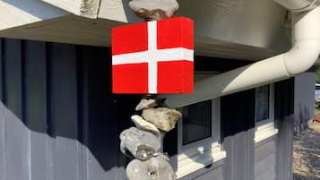 Una casa con una bandera roja y blanca colgada del tejado, una ventana y una canaleta blanca.