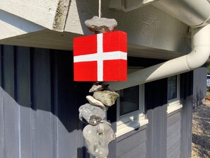 A house with a red and white flag hanging from the gutter, surrounded by rocks. - 4 Star Holiday Home in Logstor (Logstor)