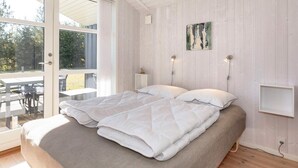 Quarto com cama, duas mesas de cabeceira, um quadro na parede e vista pela porta de vidro.