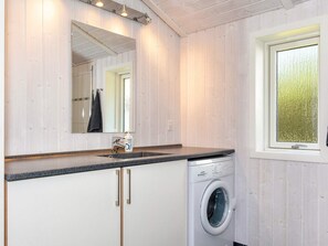 A compact laundry room with a washing machine, a sink, and a mirror. - 4 Star Holiday Home in Logstor (Logstor)