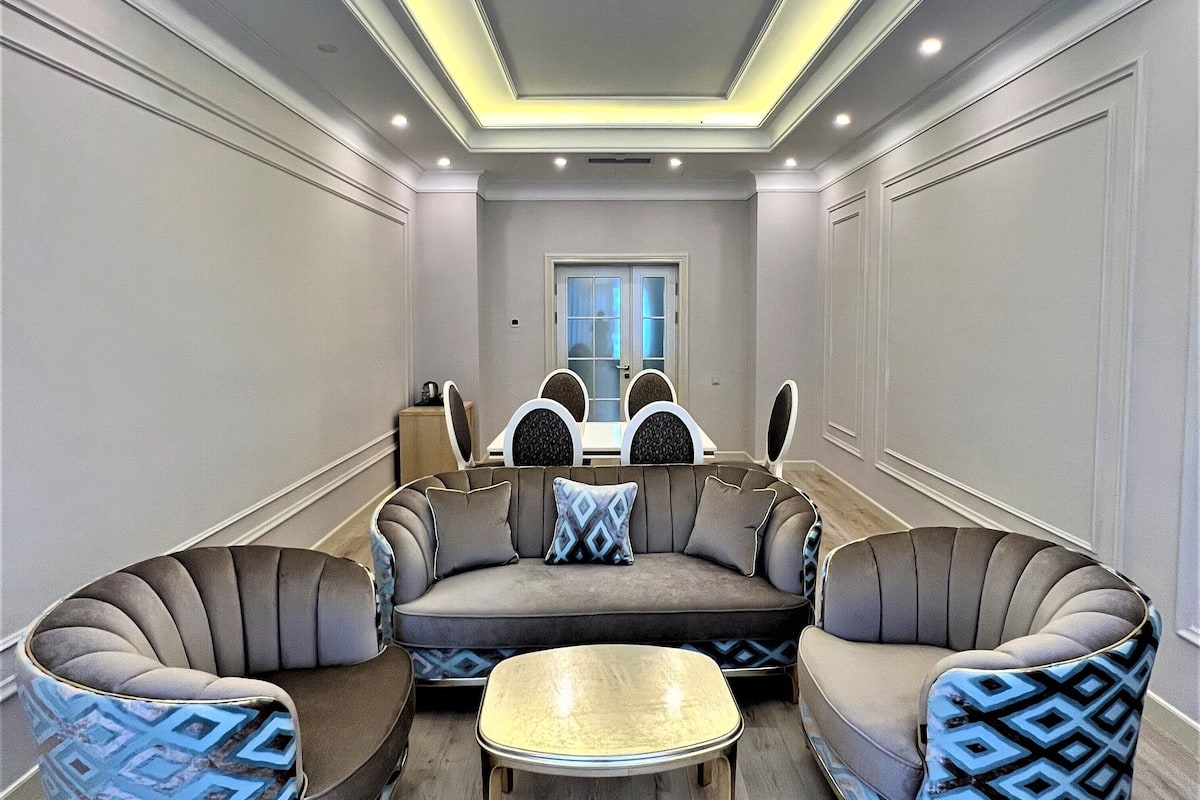 A modern living room with a curved sectional sofa, two armchairs, and a coffee table.