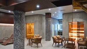 Eine moderne Lobby mit hohen Decken, Steinsäulen, Korbmöbeln und einer Glastrennwand.