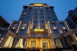 Un hotel con un llamativo letrero que dice 'HOTEL', varios pisos y un balcón con sillas.