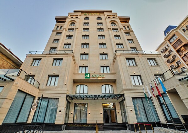 Un hotel con entrada central, varios pisos y un diseño arquitectónico moderno.