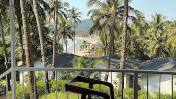 A wooden deck with a view of a beach and palm trees.