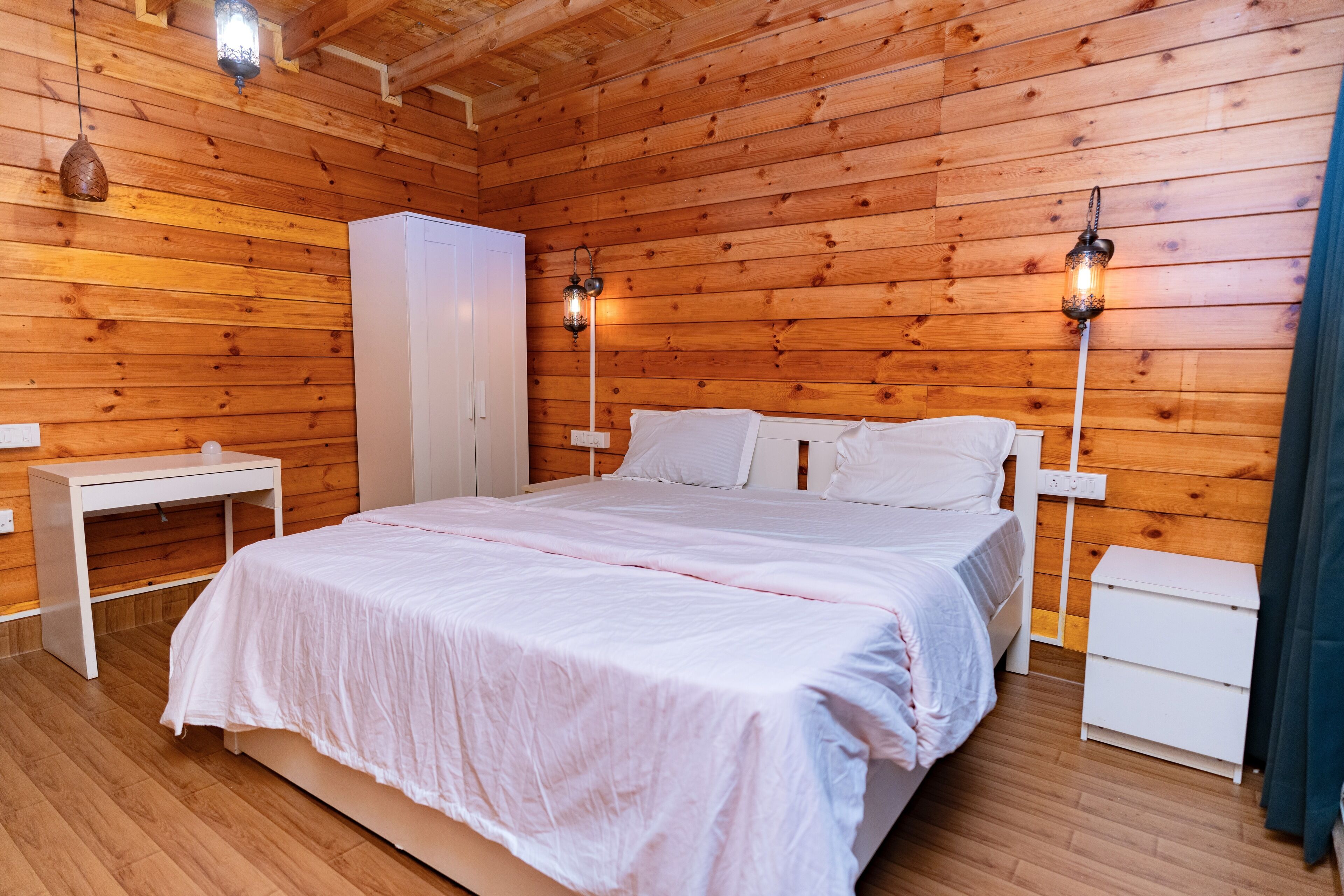 Een kamer met houten lambrisering, een bed, nachtkastjes en wandlampen.