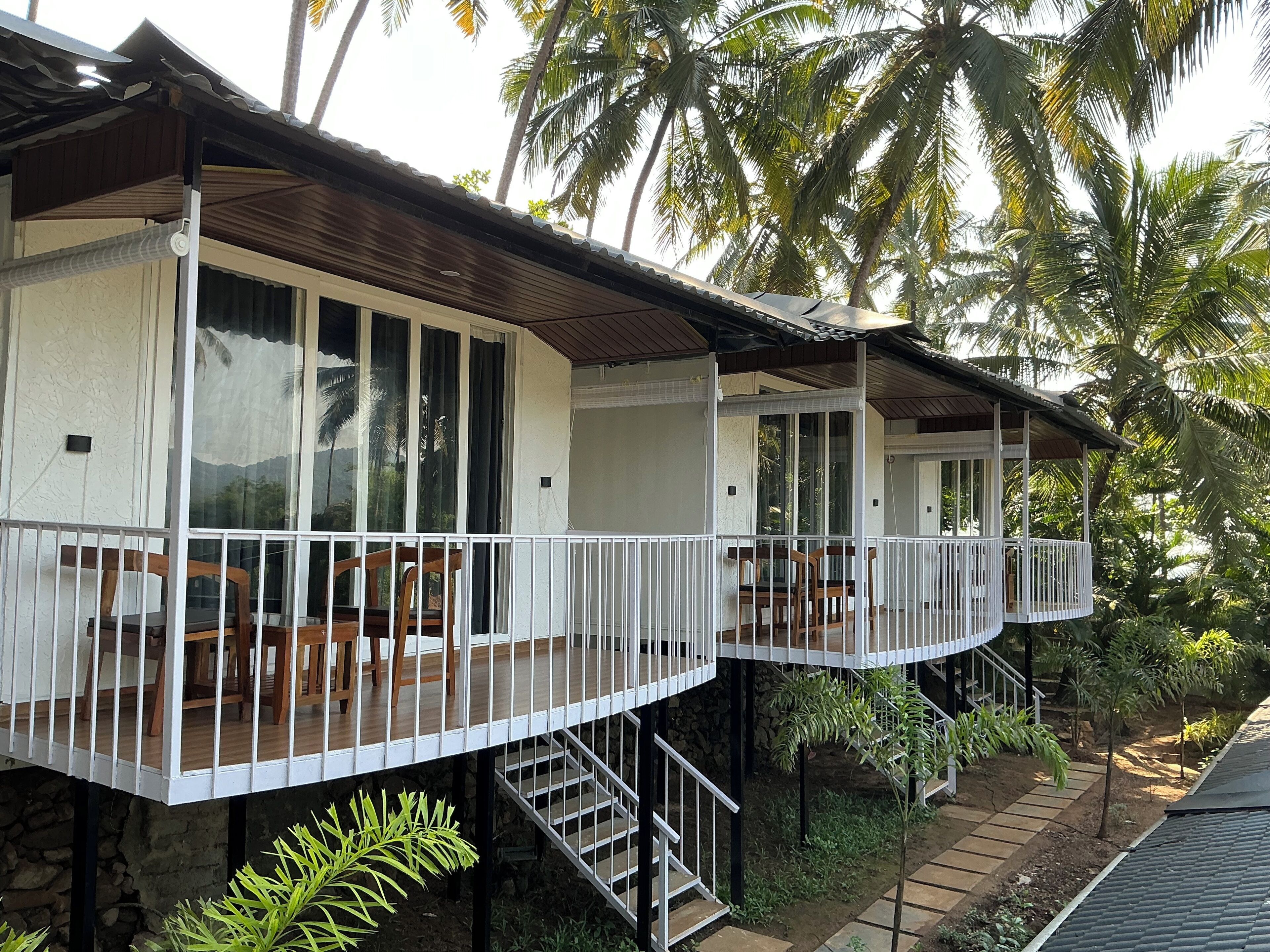 A two-story building with balconies, wooden furniture, and a stone foundation.
