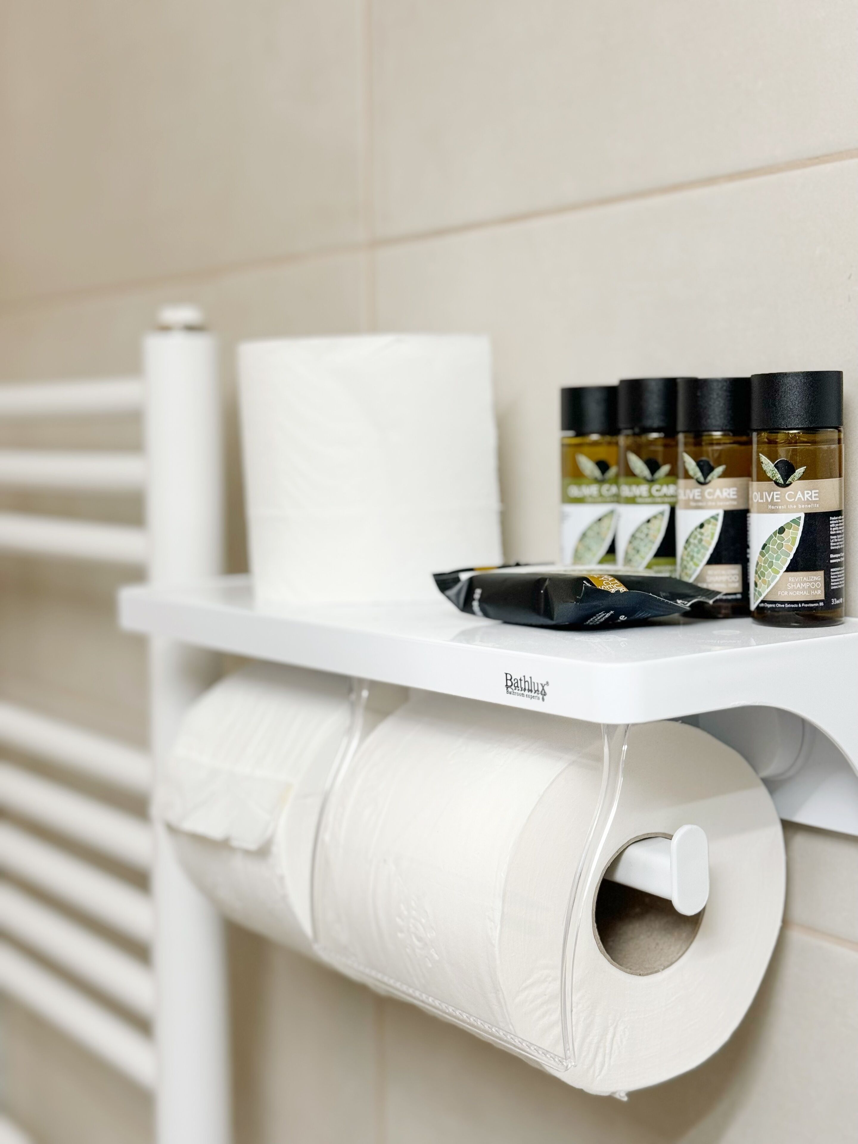 A bathroom with a white shelf holding toiletries, a roll of toilet paper, and a black hairbrush.