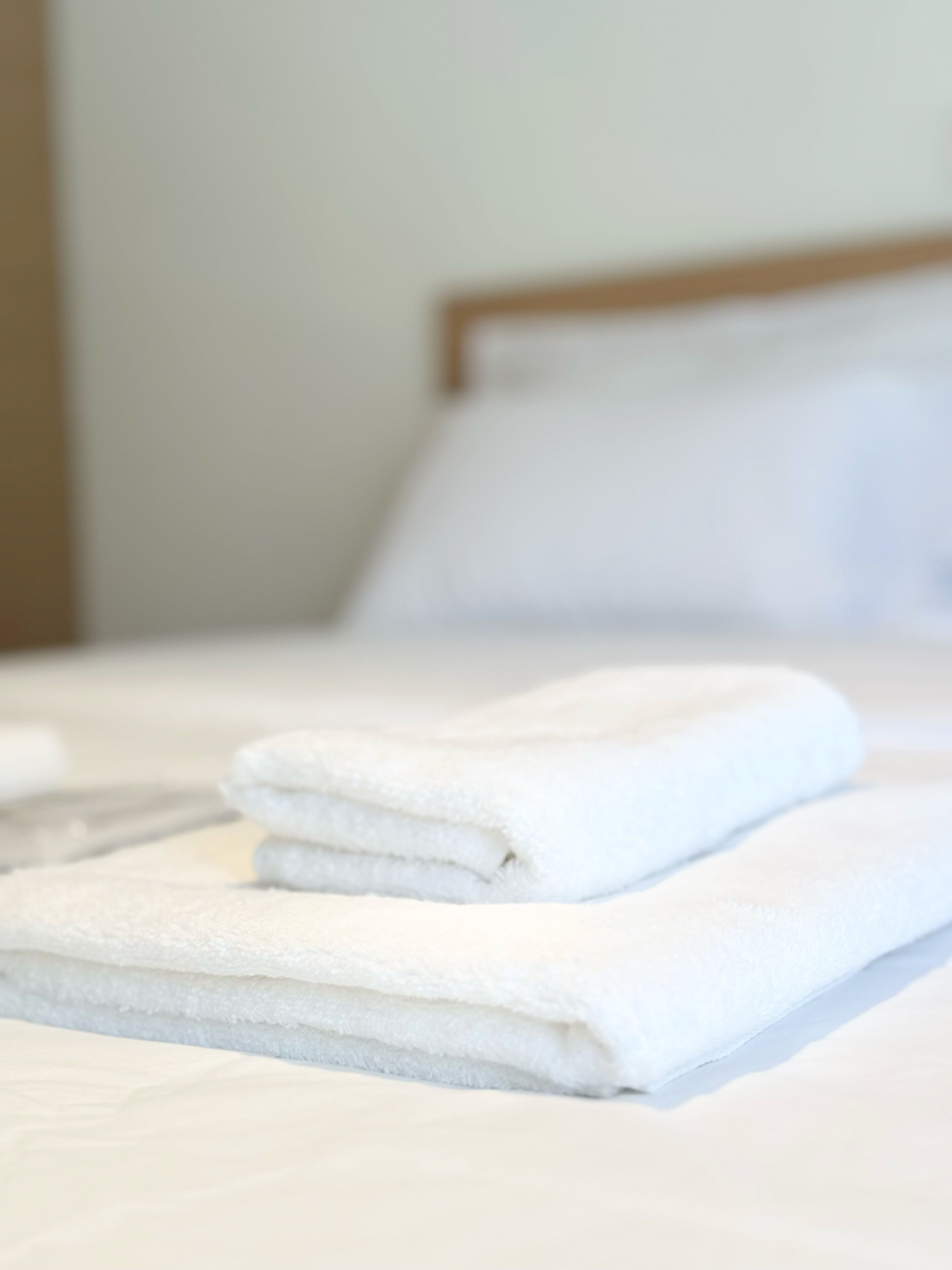 A neatly made bed with white linens and a wooden headboard.