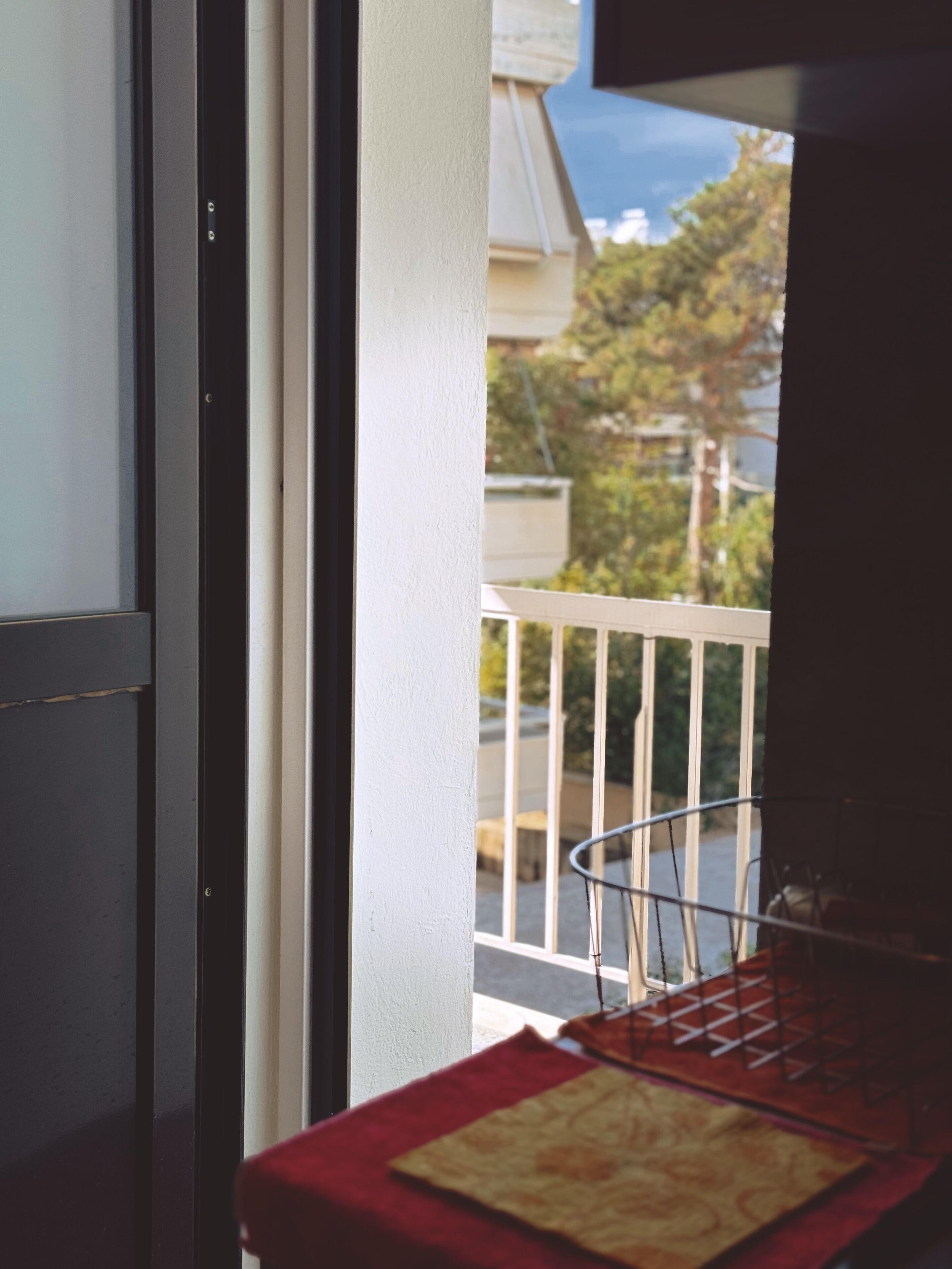 A balcony with a metal chair and a table with a red cloth.