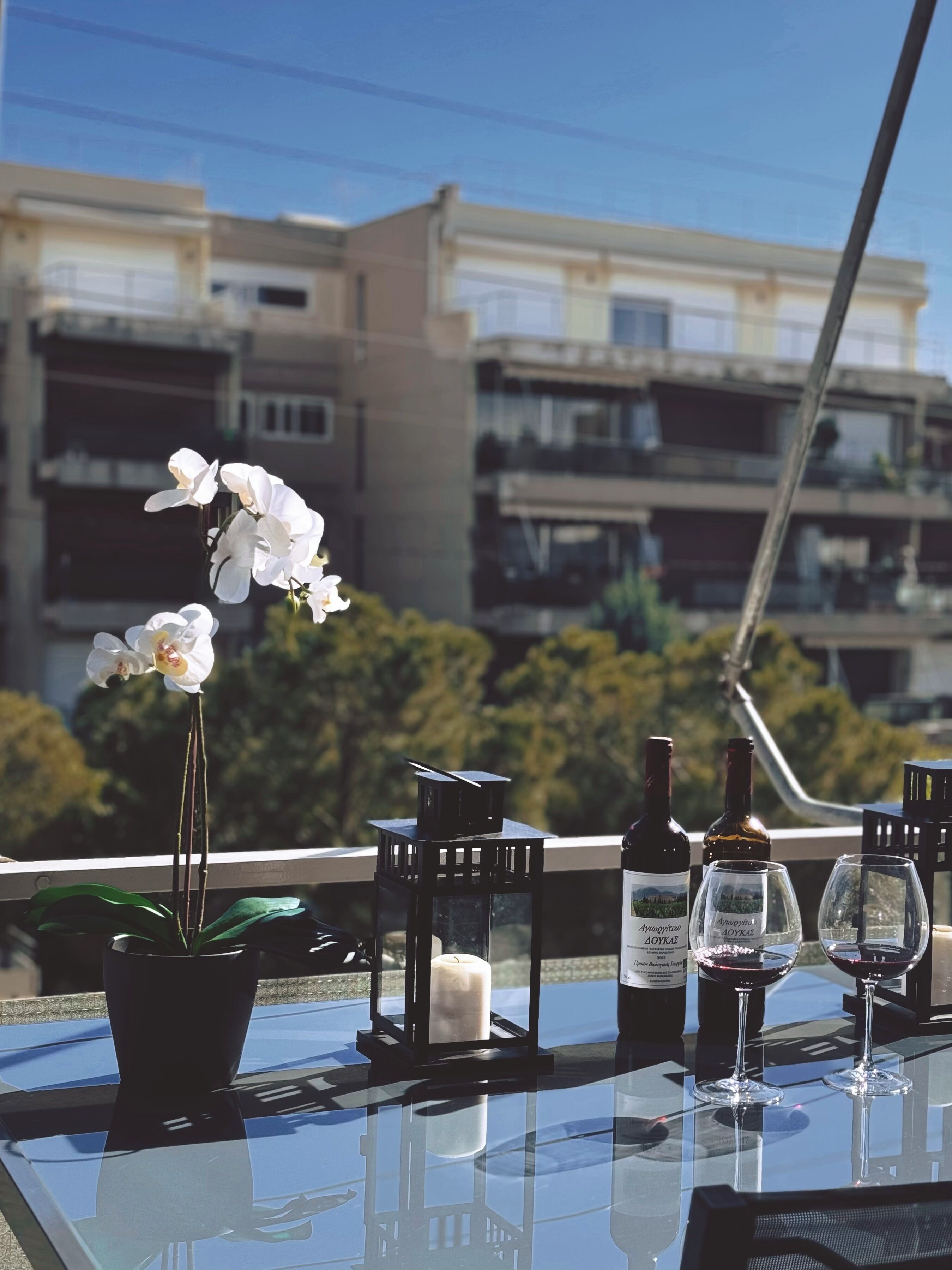 A table with two wine bottles, two glasses, a candle, and an orchid plant.