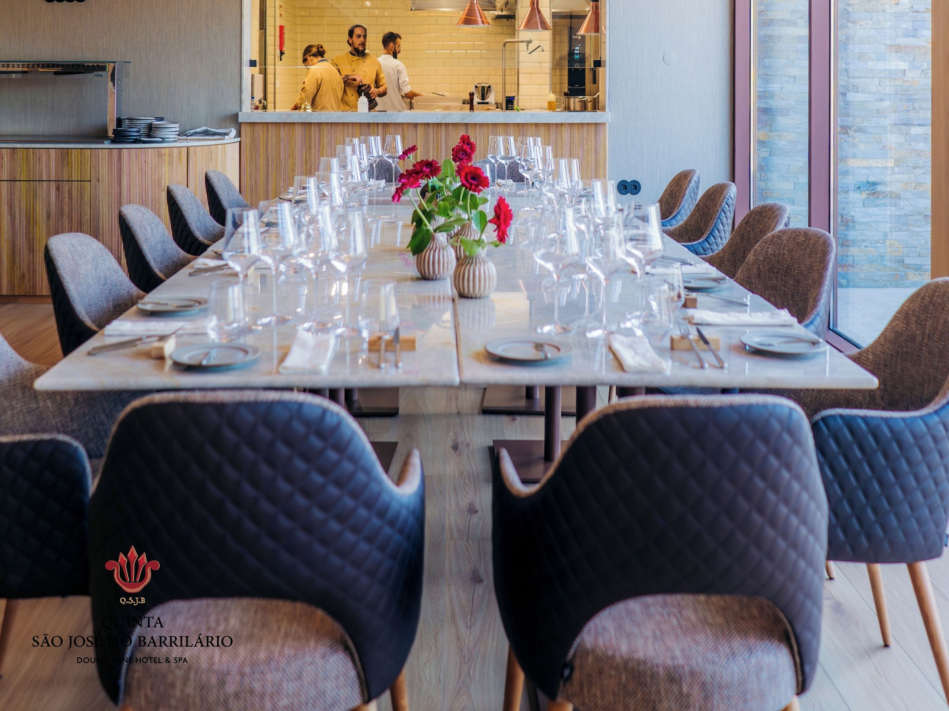 A dining area with a long table set for a meal, surrounded by upholstered chairs.