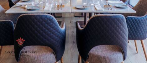 A dining area with a long table set for a meal, surrounded by upholstered chairs.