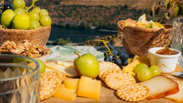 A table with cheese, crackers, grapes, nuts, and a glass of water.