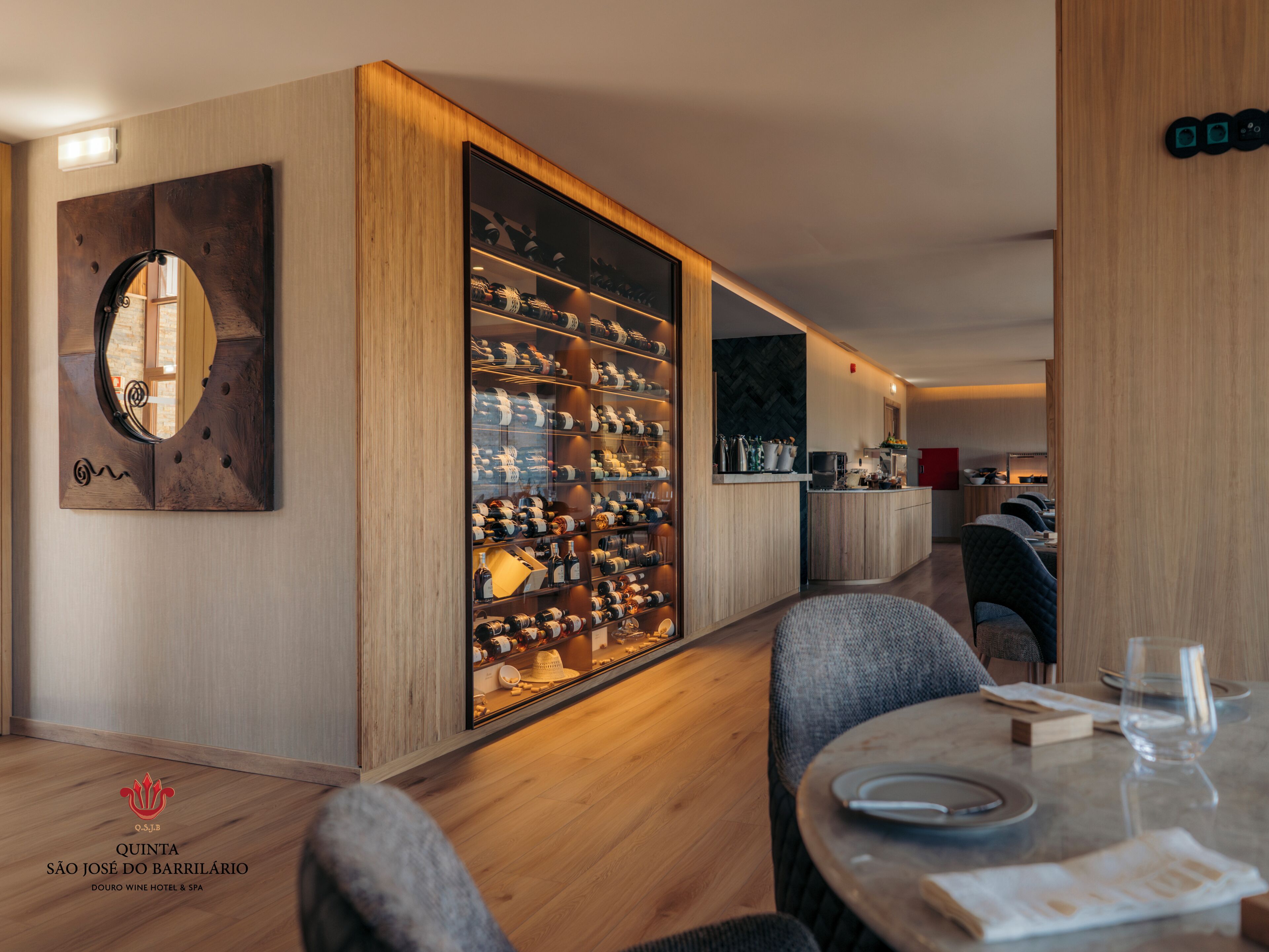 A modern hotel room with a wine cellar, a round table with chairs, and a mirror on the wall.