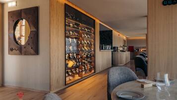 A modern hotel room with a wine cellar, a round table with chairs, and a mirror on the wall.