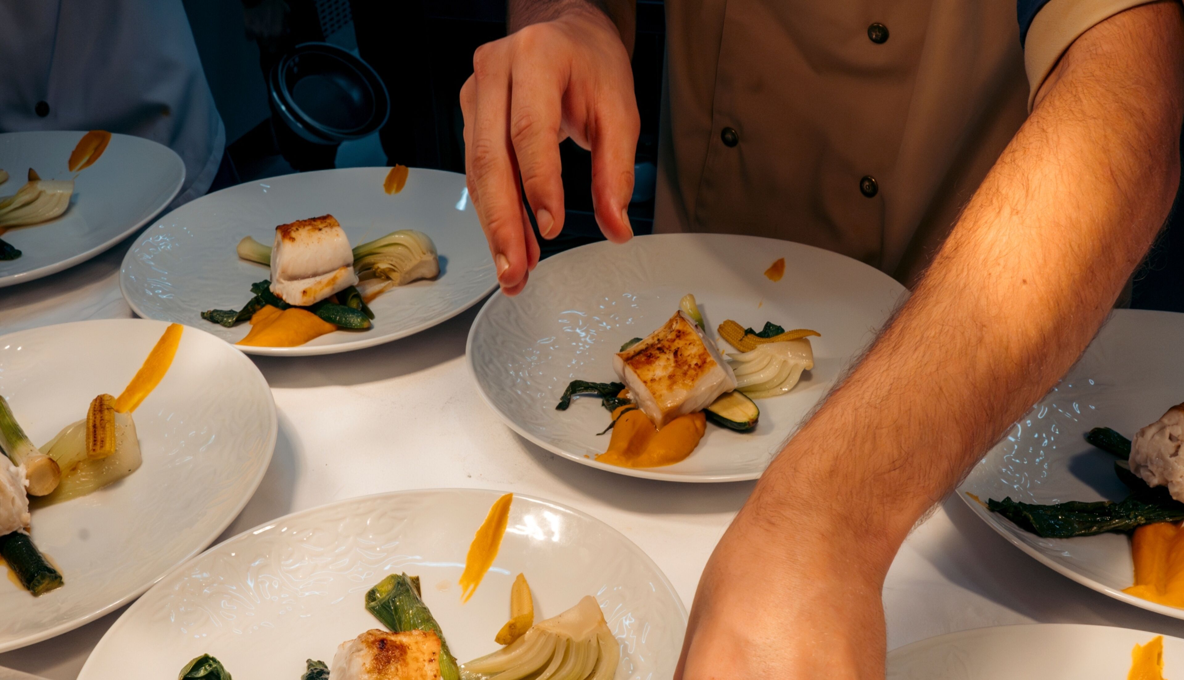 Una mesa de comedor con varios platos de comida, incluyendo pescado y verduras.
