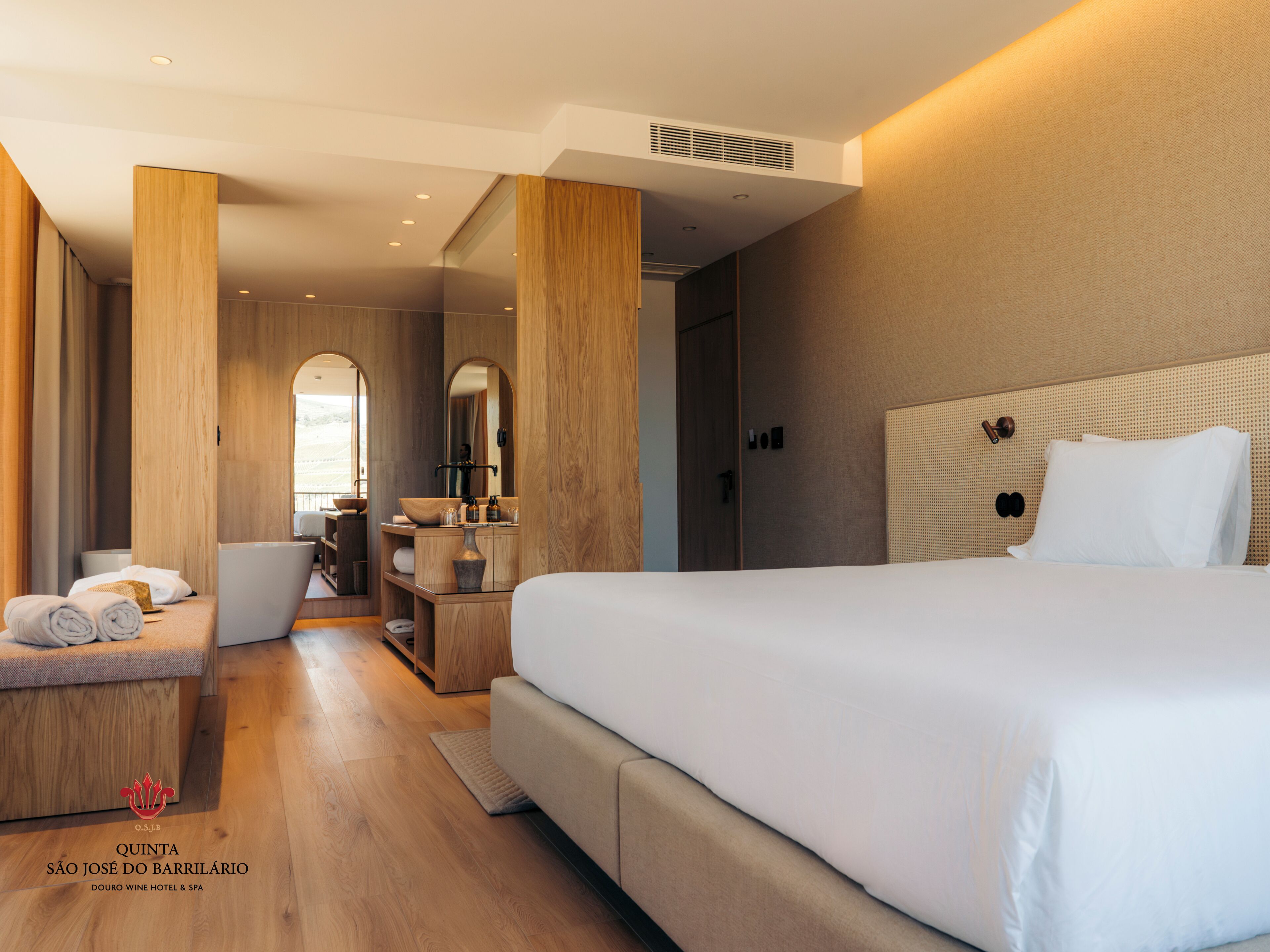 Un moderno cuarto de hotel con una cama grande, muebles de madera, un tocador con espejo y vistas al exterior.