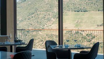 A dining area with a view of a hilly landscape.